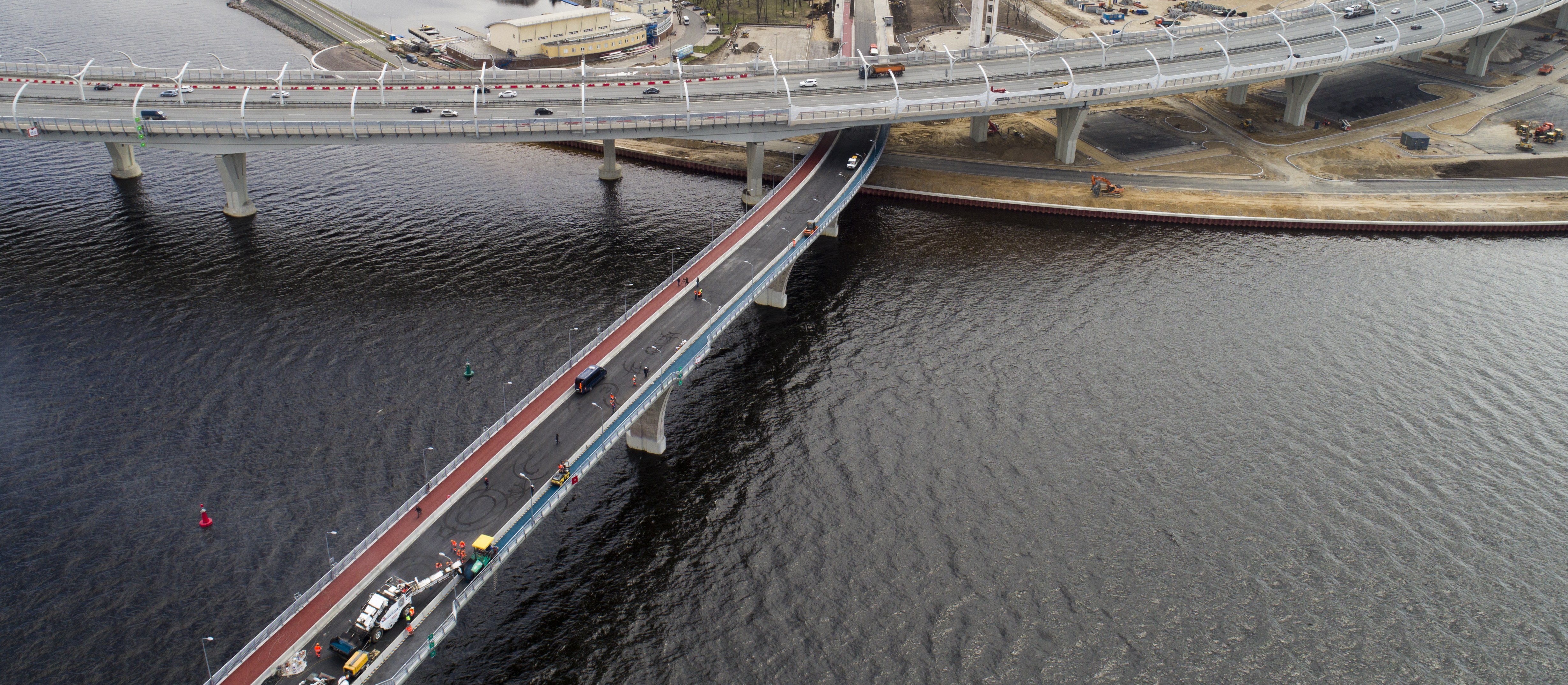 Cable-stayed bridge with adjacent coloured-asphalt path along a modern waterfront