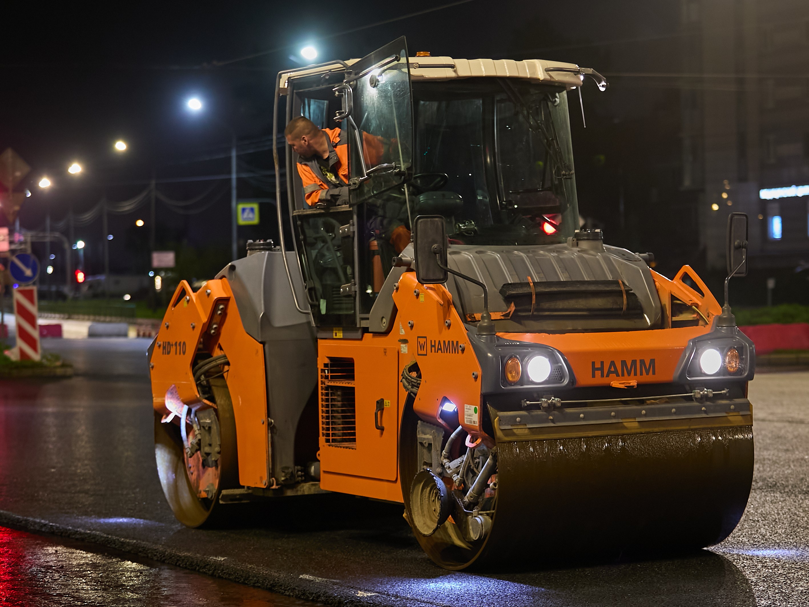Asphalt paving works at night with road rollers compacting freshly laid asphalt