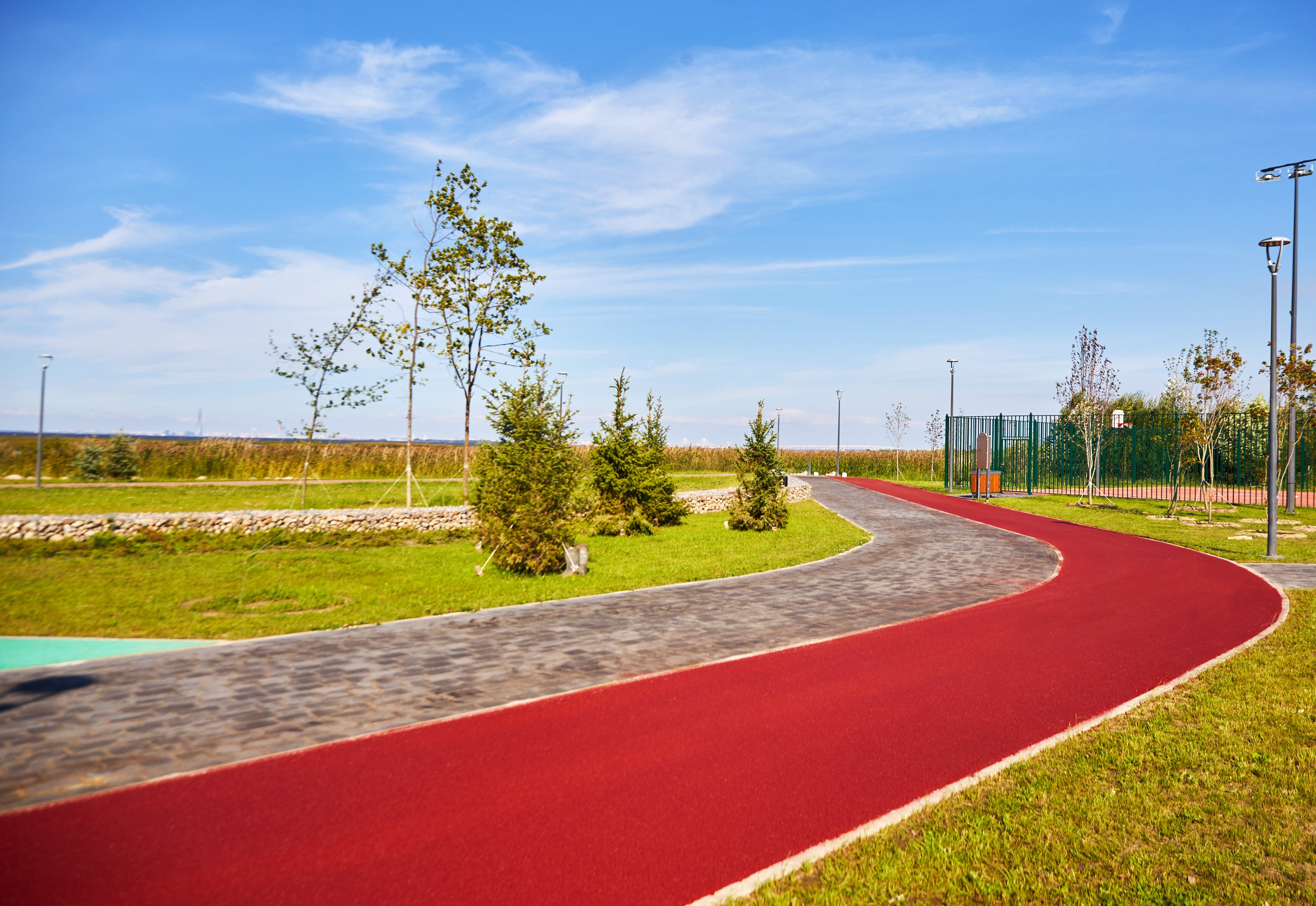 Curving red coloured-asphalt path through a public park